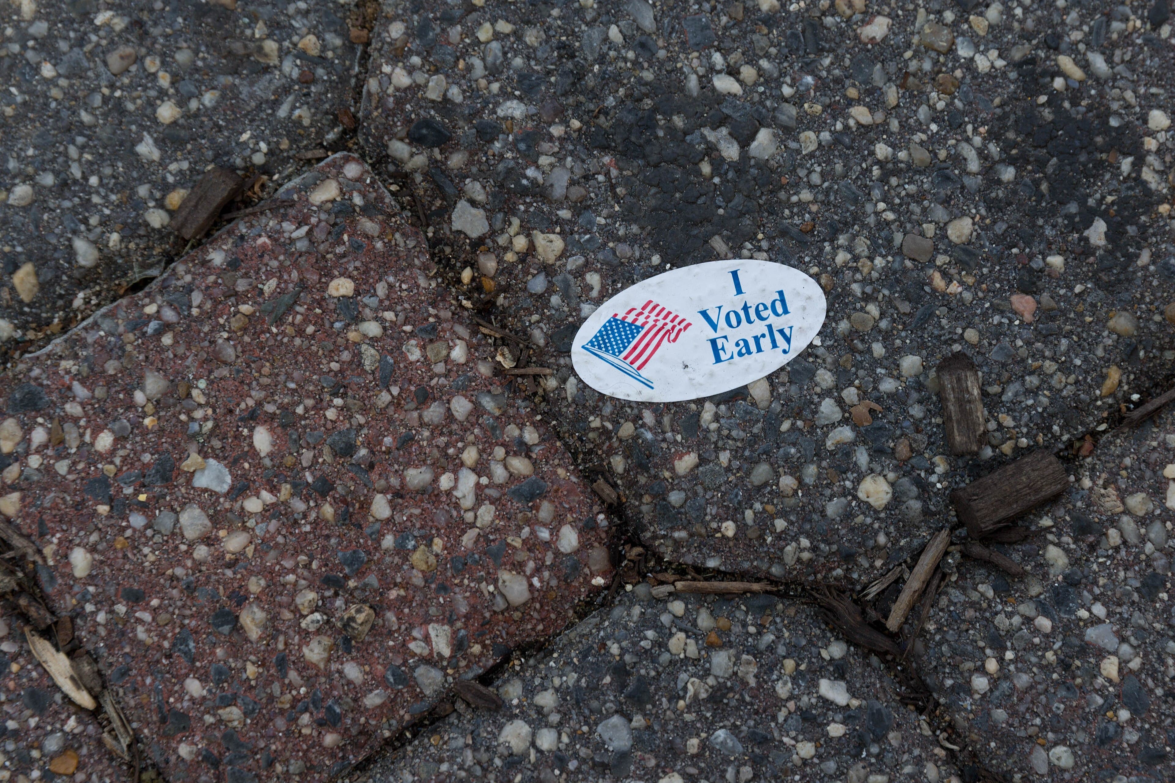 An oval "I Voted Early" sticker with an American flag lying on a stone pavement