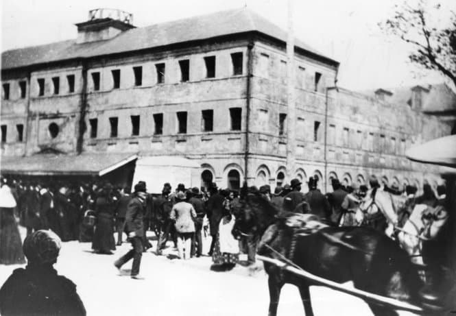 Black-and-white photograph of a large crowd gathered in the street outside the three-story Parish Prison in New Orleans