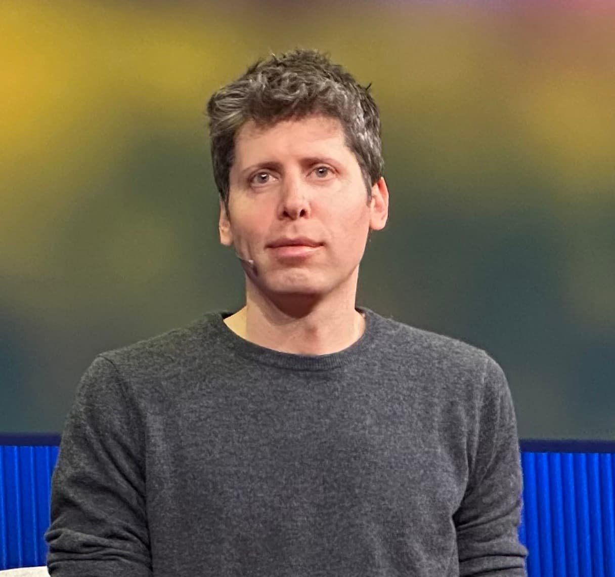 Sam Altman, wearing a gray sweater, onstage at the TED conference
